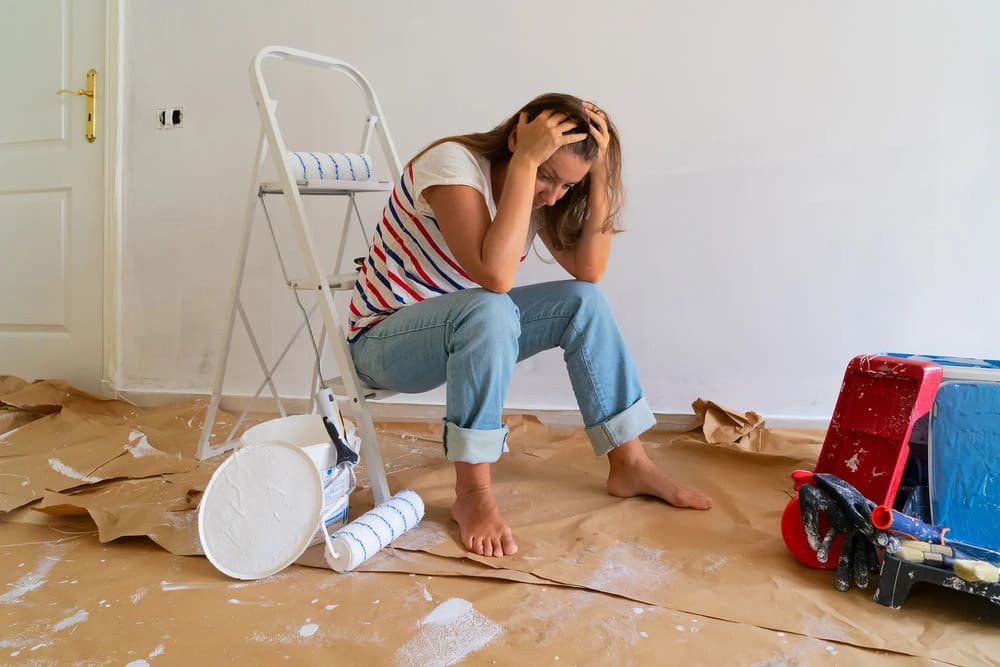 Someone sitting amidst renovation mess, visibly tired