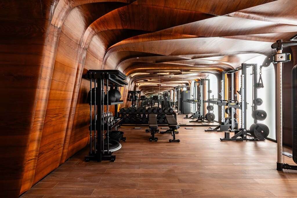 The wood-lined Fitness Center is geared with Technogym equipment at the Hotel Romeo Roma by Zaha Hadid Architects
