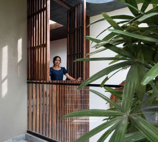 Woman looking out of an opened window with few leaves in the front. A circular skylight streams sunlight onto the interior