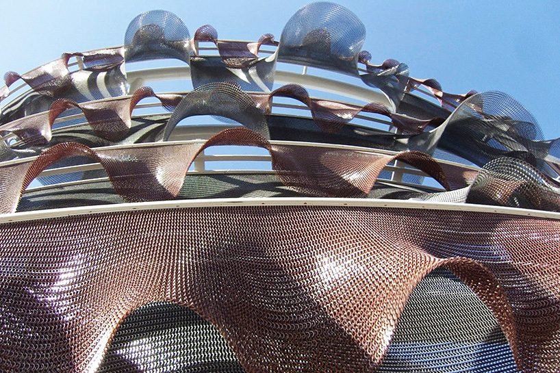 Lattice structure made from interlocking recycled plastic panels forming a chainmail-like pavilion.