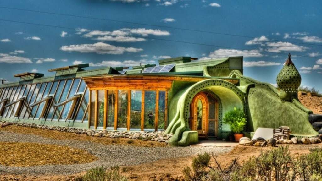 Earthship homes built from natural and recycled materials such as tires, glass bottles, and cans, showcasing a sustainable off-the-grid living solution