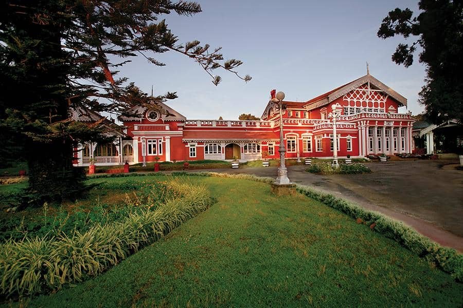 Victorian-style heritage palace in Ooty surrounded by gardens, with wooden gables, Swiss chalet influence, and colonial Gothic detailing.