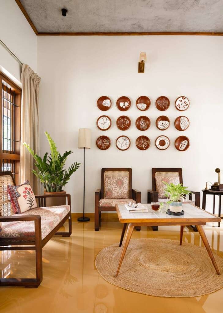 earthy indian living room with stone flooring, wooden chairs and terracotta plates displayed on wall