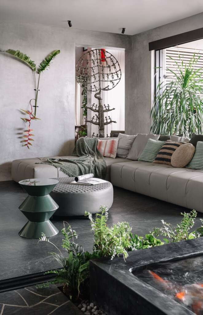 a biophilic living room with greenery, koi pond and stone flooring against a muted grey colour palette