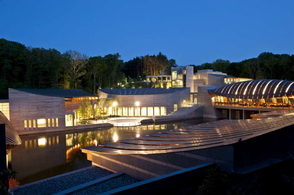 The Crystal Bridges Museum of American Art, designed by Safdie Architects, nestled in the Ozark woods with its flowing design.