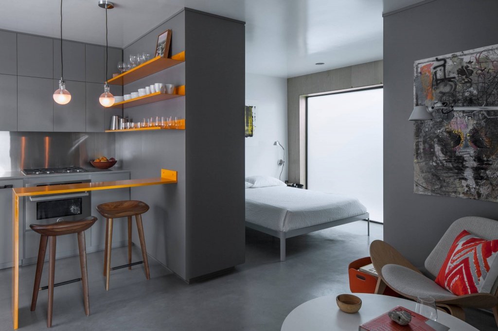 A studio apartment with large windows letting in natural light, creating a cozy and stylish living space