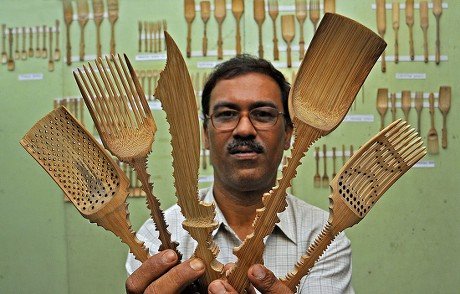 a man holding cutlery made of bamboo in his hands
