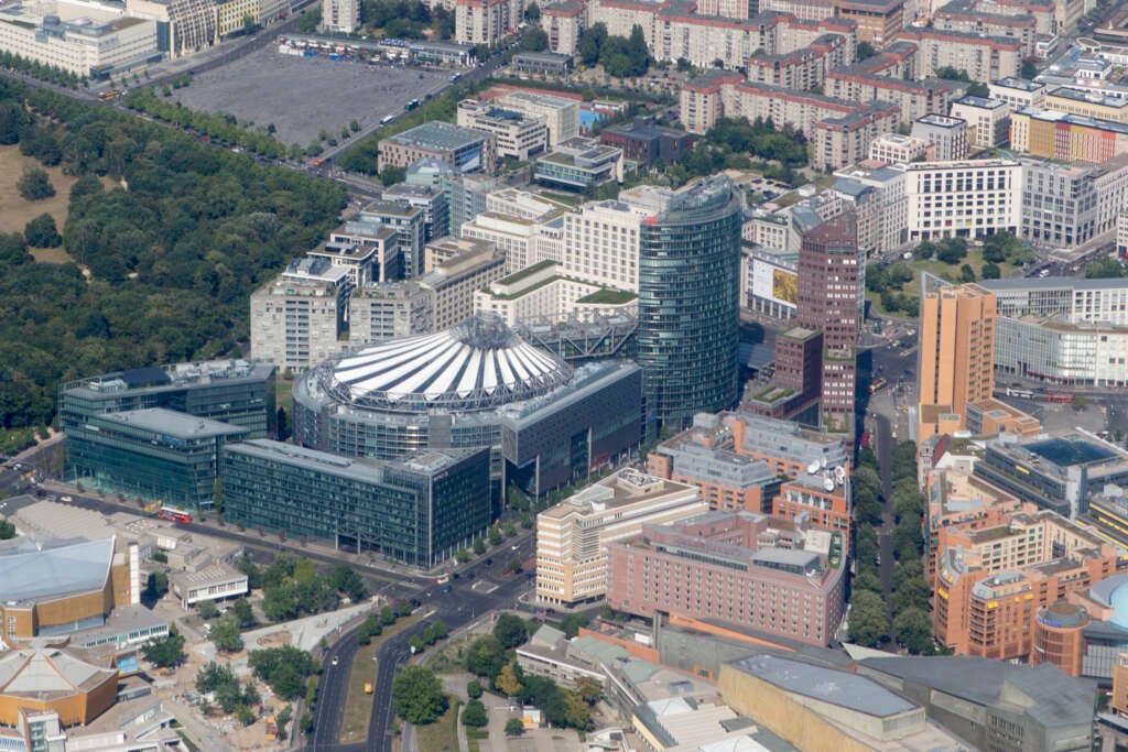 Aerial view of Potsdamer Platz in Berlin featuring the Sony Center’s white canopy roof, modern skyscrapers, and surrounding city blocks.