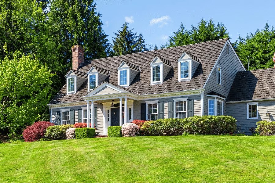 A classic cottage-style residence featuring dormer windows, a prominent roof, and a meticulously kept front yard.