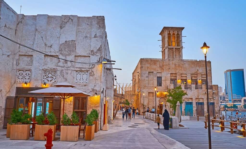 street view of al fahidi neighbourhood showing buildings of gypsum, coral and stone glowing at sunset