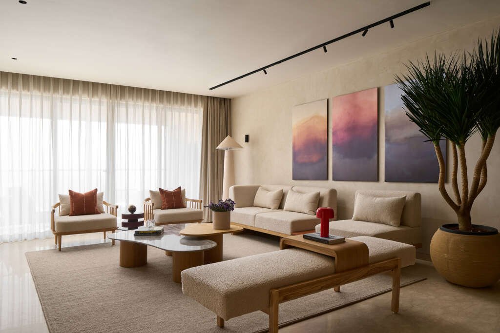 living room with a sofa set, floor lamp, planter and backed by a three piece artwork