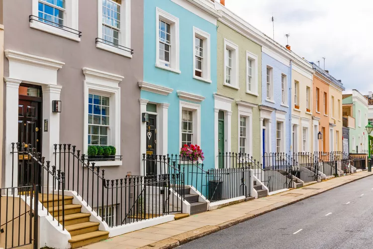 A colourful line of classic row houses with pastel facades, featuring black railings and stone staircases.
