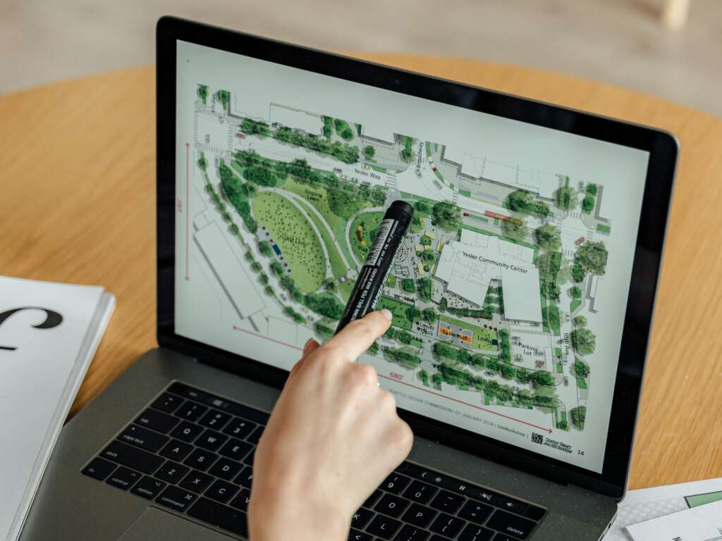 Generalist Vs. Specialist Architect: What Does The World Need Today? 1 a sustainability specialist architect pointing to a design plan on the laptop screen