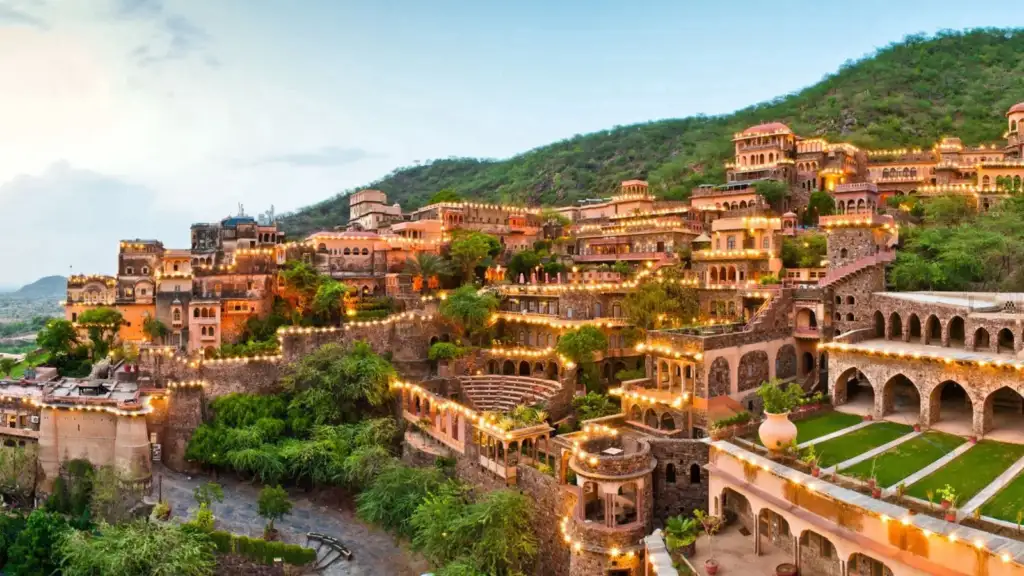 Majestic Neemrana Fort Palace built into a hillside with layered terraces, Rajasthani stonework, and arched balconies.