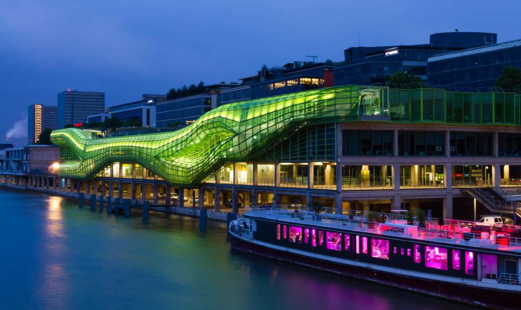 night view of cite de la mode et du design, paris from river with bright neon lights