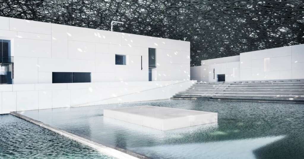 Louvre Abu Dhabi Architecture: How Light, Shadow And Culture Come Together 2 reflective water features surrounding louvre abu dhabi with the dome mirrored across the surface.